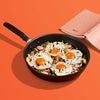 Accent nonstick skillet with fried eggs alongside a book